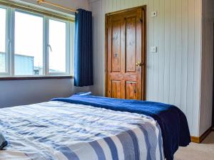 een slaapkamer met een bed met een blauwe en witte deken bij Little Fern in Sourton