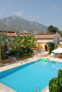 a large blue swimming pool with a mountain in the background at Five Fingers Holiday Bungalows in Kyrenia