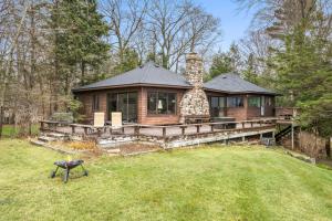 a log home with a large deck and a grill at Lakefront House by Michigan Waterfront Luxury Properties in Norton Shores