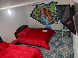 Un dormitorio con una cama roja y una pintura de un leopardo en La Cachaca, en Bogotá