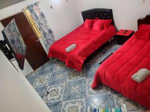 1 Schlafzimmer mit 2 Betten mit roter Bettwäsche und einem Boden in der Unterkunft La Cachaca in Bogotá