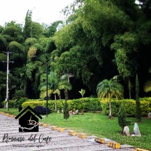 un parc avec des arbres et un panneau dans l'herbe dans l'établissement Remanso del café, à La Tebaida