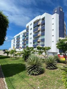 um grande edifício branco com plantas em frente em Apartamento Pe na areia do Bessa em João Pessoa