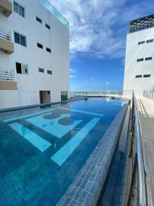 uma piscina em frente a um edifício em Apartamento Pe na areia do Bessa em João Pessoa