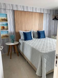 若昂佩索阿的住宿－Apartamento Pe na areia do Bessa，一间卧室配有一张带蓝色枕头的床和一张桌子