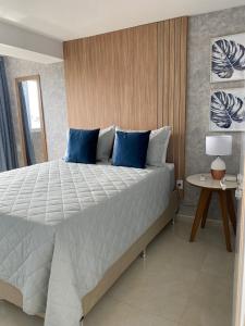 um quarto com uma cama grande e almofadas azuis em Apartamento Pe na areia do Bessa em João Pessoa