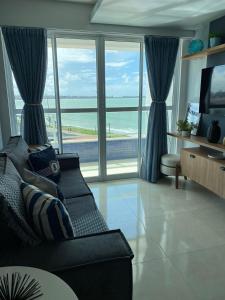 uma sala de estar com um sofá e vista para o oceano em Apartamento Pe na areia do Bessa em João Pessoa