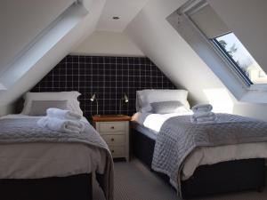 a attic bedroom with two beds and two windows at Briar Cottage in Gargunnock