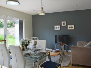 a living room with a table and a tv at Briar Cottage in Gargunnock