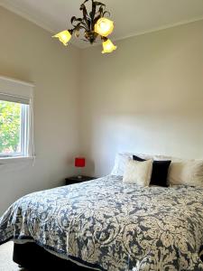 a bedroom with a bed and a chandelier at Cherry Blossom Cottage - Beechworth-Getaways in Beechworth