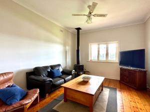 una sala de estar con un sofá y una mesa en Cherry Blossom Cottage - Beechworth-Getaways, en Beechworth