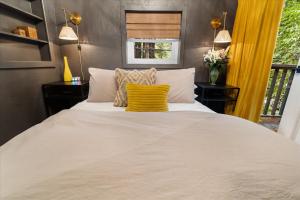 1 dormitorio con 1 cama blanca grande con almohadas amarillas en The Black Nest - Hot Tub Romantic Getaway, en Guerneville