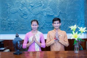 Un uomo e una donna in piedi davanti a una statua. di Reaksmey Chanreas Hotel a Siem Reap