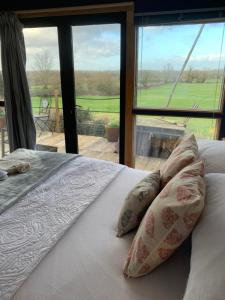 a bed with pillows in front of a window at Countryside Garden Summer House in Calne