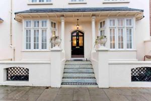 a white house with a black door and stairs at Beautiful 4 Bed House by Regents Park in London