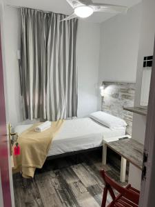 Habitación pequeña con cama y ventana en Casa de Huéspedes Almansa, en Madrid