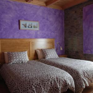 2 camas en un dormitorio con paredes moradas en La Senra, en León