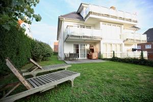 una casa blanca con un banco en el patio en Villa Verdi - Ferienwohnung 4 en Wangerooge