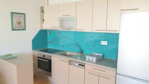 eine Küche mit weißen Schränken und einer blauen Wand in der Unterkunft ELEGANCE Apartment in Sarajevo