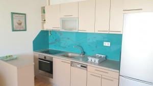 a kitchen with white cabinets and a blue wall at ELEGANCE Apartment in Sarajevo