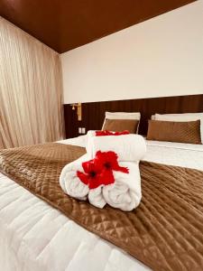 Una habitación de hotel con una cama con toallas y flores en Refúgio da Rita, en Fernando de Noronha