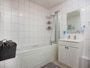 Baño de azulejos blancos con bañera y lavamanos en Jubilee Cottage en Dawlish