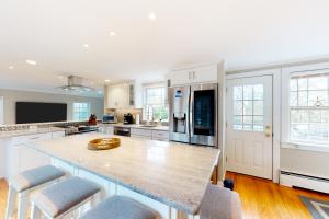 a large kitchen with a large wooden island with chairs at Chatham Living in Chatham