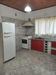 cocina con nevera blanca y armarios rojos en Alojamientos Litoral - Casa Palma en Gualeguaychú