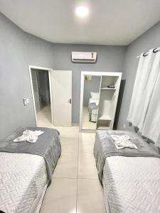 Habitación con 2 camas y espejo. en Casa Flat Caminho da Praia, en Maragogi