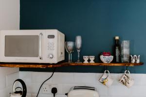 a microwave sitting on a shelf above a kitchen counter at The Snug at Caphays: perfect rural retreat in Long Burton