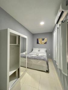 Dormitorio pequeño con cama y espejo en Casa Flat Caminho da Praia, en Maragogi