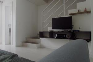 a living room with a flat screen tv and stairs at Sobrado Carpe Diem Palmeiras, 450 m da praia, 2 suítes com ar, 2 vagas, check-in 24h, churrasqueira, 20 min do Beto Carrero in Piçarras