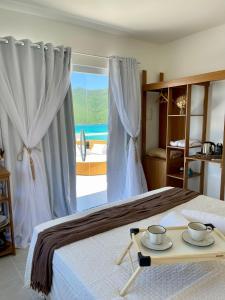 1 dormitorio con 1 cama con 2 tazas en una bandeja en Casa aconchegante Pontal do Atalaia Vista Mar, en Arraial do Cabo