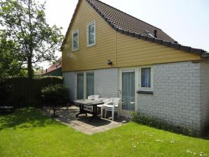 a house with a table and chairs in the yard at Nice holiday home with sauna, in a holiday park only 200m away from the beach in Wemeldinge