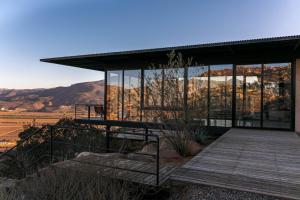 a house with glass windows and a wooden deck at Villa Garven in Valle de Guadalupe