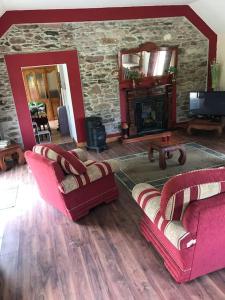a living room with two chairs and a stone fireplace at Castlegregory-Seaside 2 Bedroomed Cottage in Castlegregory