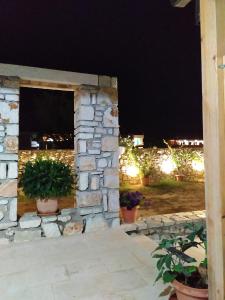 una pared de piedra con macetas en un patio por la noche en Tonea's Houses en Himare