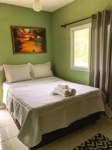 Un dormitorio verde con una cama con toallas. en Sítio Adonai Pousada & Eventos en Guarapari