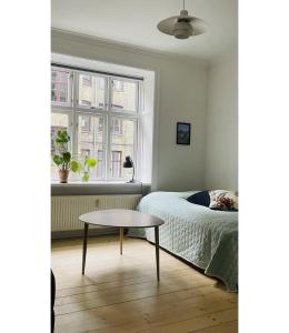 コペンハーゲンにあるApartmentInCopenhagen Apartment 1310のベッドルーム1室(ベッド1台、テーブル、窓付)