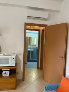 Zimmer mit einer Mikrowelle und einer Tür zur Küche in der Unterkunft Belmare trilocale a piano terra indipendente in San Vito lo Capo