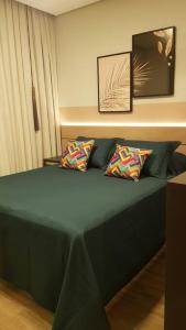 a green bed with two pillows on top of it at Studio com piscina Ingleses Florianópolis 202 in Florianópolis