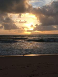 una puesta de sol en la playa con el océano en Casa do italiano, en Maceió