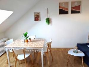 une salle à manger avec une table et des chaises blanches dans l'établissement Paisible duplex au centre-ville, au Mans