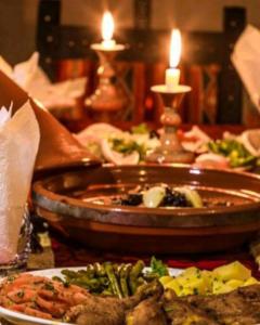 a table with a plate of food on a table with candles at Authentic Desert Luxury Camp in Merzouga