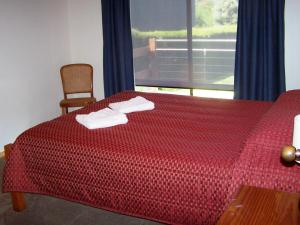 um quarto com uma cama vermelha com duas toalhas em Hazards House em Coles Bay