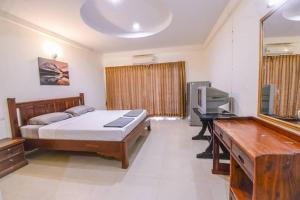 a bedroom with a bed and a desk and a television at We Residence in Pattaya Central