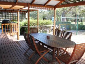 uma mesa e cadeiras de madeira num deque de madeira em Hazards House em Coles Bay