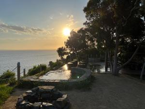 a swimming pool next to the ocean at sunset at Fairview Lakeside Cottage Metung in Metung