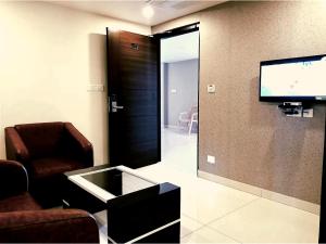 HOTEL VINTAGE CASTLE في كويمباتور: غرفة معيشة مع تلفزيون وكرسي ومرآة