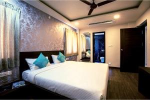 a bedroom with a large white bed with blue pillows at HOTEL VINTAGE CASTLE in Coimbatore